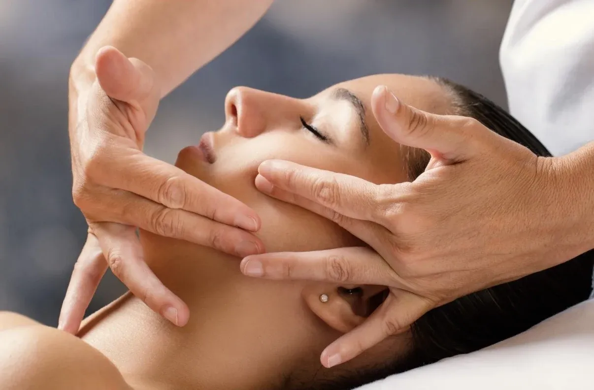 Connective tissue facial massage performed with hands along the cheeks and jaw